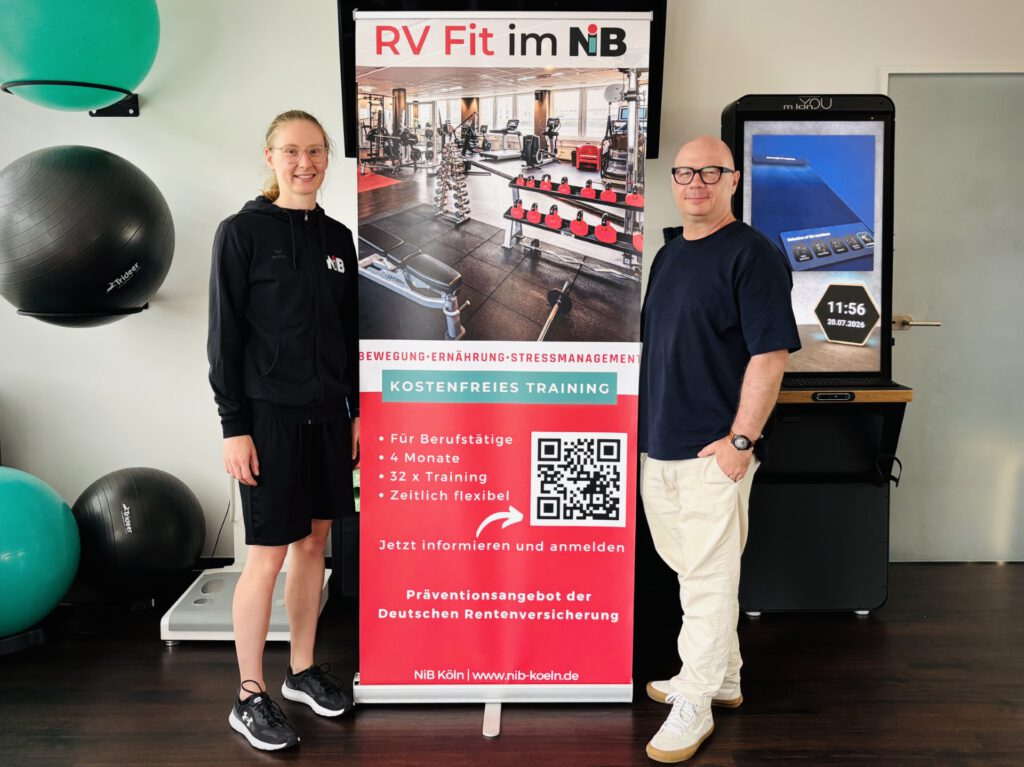 Zwei Personen stehen neben einem Roll-up für das kostenlose RV-Fit-Präventionsprogramm von NiB Köln